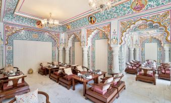 a luxurious living room with ornate decorations , including columns and chandeliers , as well as several couches and chairs arranged around a central dining at Resort Rio