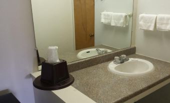 a bathroom with a sink , toilet , and mirror , as well as towels on the counter at H&K Motel