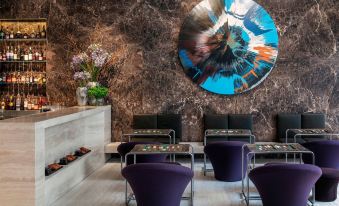 a modern room with purple chairs and a large circular painting on the wall , creating an artistic atmosphere at The Jaffa, a Luxury Collection Hotel, Tel Aviv