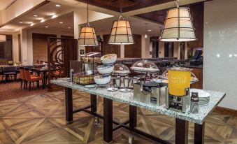 a dining area with a variety of food and drinks on display , including a table with a variety of bowls and cups at Hilton Garden Inn Uniontown