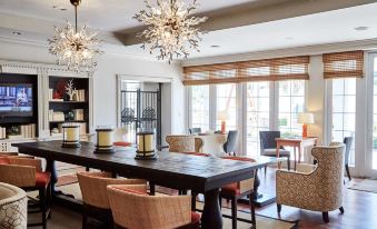 a large dining table with chairs is surrounded by a living room with couches and chandeliers at Wild Dunes Resort