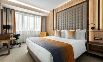 a large bed with a white and brown blanket is in the center of a room at Ramada by Wyndham Ramnicu Valcea