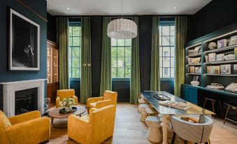 a modern living room with yellow chairs , a dining table , and large windows , creating a warm and inviting atmosphere at Cheval Old Town Chambers