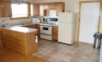 a kitchen with wooden cabinets , a white refrigerator , and a wooden countertop has a sink , refrigerator , and microwave at Adventure High