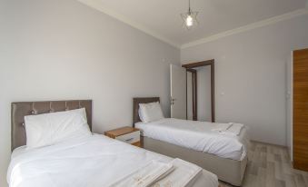 a white bedroom with two twin beds , one on the left and one on the right side of the room at Prime Inn