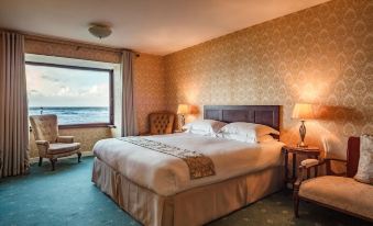 a large bed with white linens is situated in a room with a window and two lamps at Sandhouse Hotel