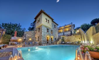 a beautiful stone building with a swimming pool , surrounded by lush greenery and lit up at night at Hotel Petradi