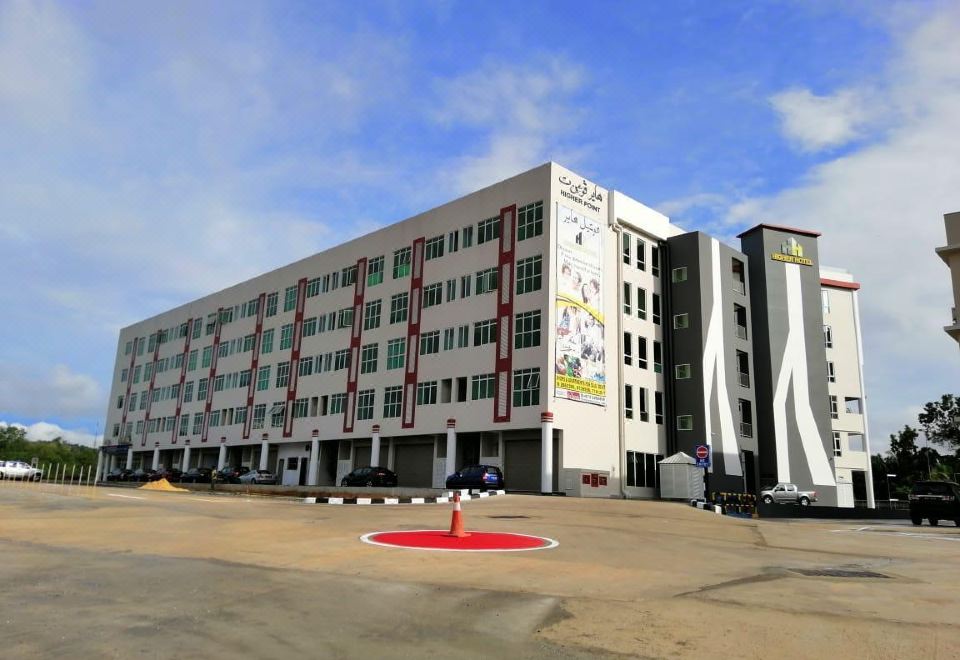 a large white building with a mural on the side , situated next to a parking lot at Higher Hotel
