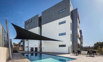 a modern building with a black and white exterior has a swimming pool in front of it at Quest Wodonga