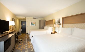 a hotel room with two beds , a desk , and a painting on the wall , along with other amenities and amenities at Holiday Inn Morgantown - Reading Area