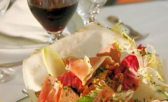 a plate of food on a dining table , accompanied by a glass of wine and a fork at Posadas de Espana Malaga