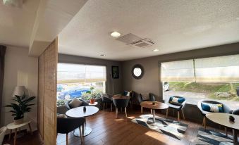 a modern living room with wooden floors , large windows , and various seating arrangements , including couches and chairs at Campanile Villejust - ZA Courtaboeuf