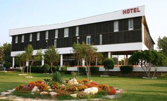 a large white hotel surrounded by a lush green lawn , with trees and flowers in the foreground at Liberty Hotel