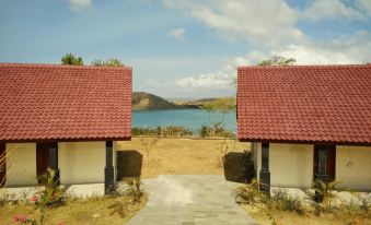 a beautiful view of a beach with two red - roofed buildings and a walkway leading to the water at Tunak Cottage