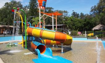 a colorful water park with various slides and play structures , set against a blue sky at Discovery Parks - Emerald Beach
