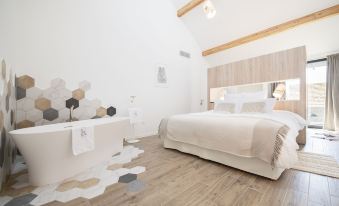 a modern bedroom with a large bed , hardwood floors , and a hexagonal patterned rug on the floor at Au Clos du Lac