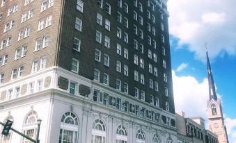 a large brick building with a steeple in the background , surrounded by a crowd of people at Francis Marion Hotel