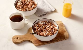 two white bowls filled with granola and a cup of coffee on a wooden cutting board at Residence Inn Riverside Moreno Valley