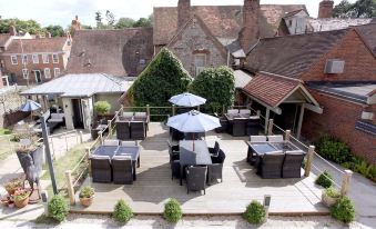 an outdoor dining area with a variety of chairs and tables , surrounded by a brick building at The White Hart