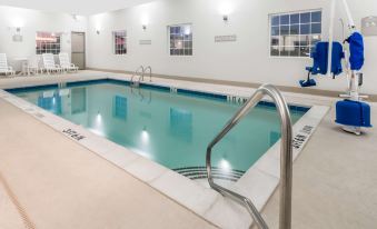 a large swimming pool with a ladder and railing is surrounded by windows and has a chair nearby at Microtel Inn & Suites by Wyndham Sweetwater