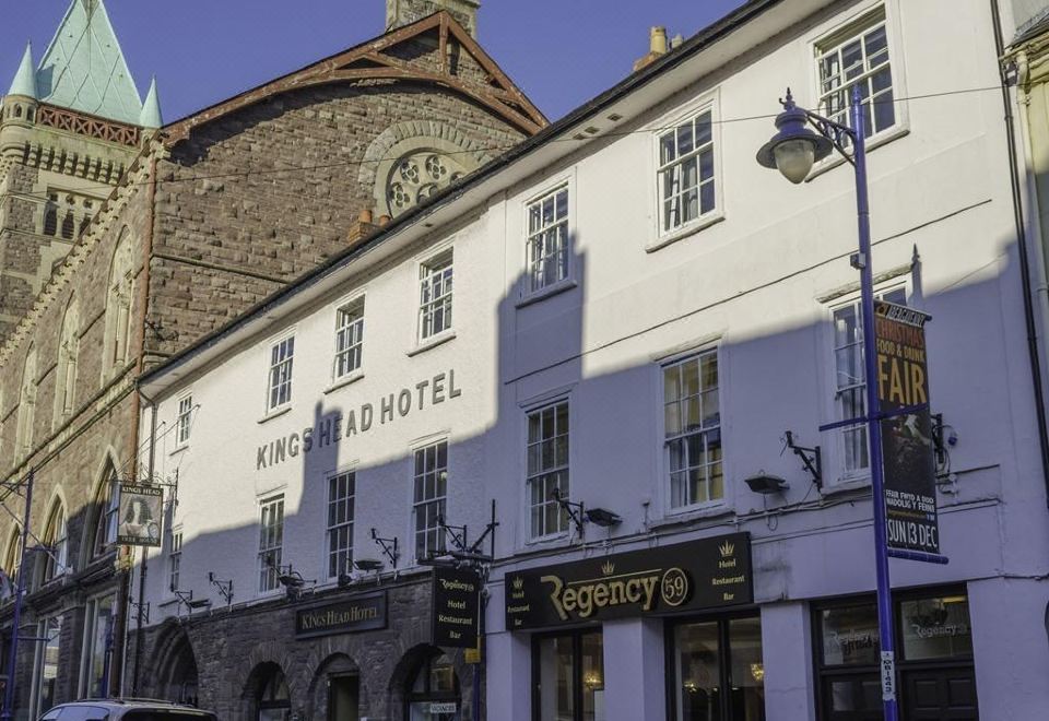 "a white building with the words "" the king 's head hotel "" on its side , situated in a city street" at The Kings Head Hotel