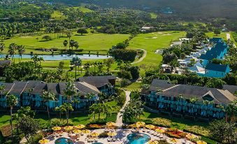 a resort with a pool surrounded by multiple buildings , trees , and mountains in the background at Four Seasons Resort Nevis