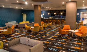 a modern lounge area with colorful chairs and tables , a bar , and blue walls , possibly in a hotel or conference room at Marriott Maracay Golf Resort