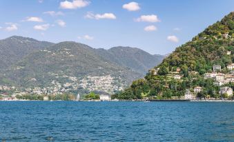 a beautiful view of a lake surrounded by mountains , with a city in the background at Ibis Como