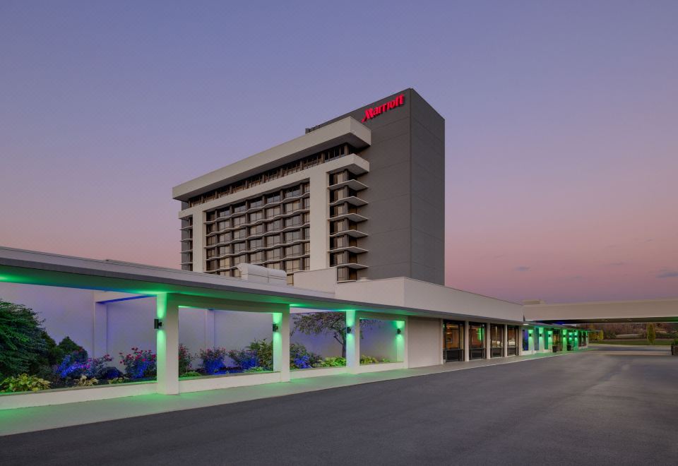 a large hotel building with a green roof , situated on a parking lot at dusk at Marriott Saddle Brook