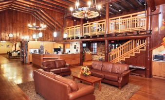 a spacious living room with wooden walls , leather furniture , and a staircase leading to the second floor at Cumberland Falls State Resort Park