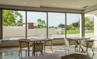 a room with wooden chairs and tables is shown with large windows overlooking a field at Paradise Resort