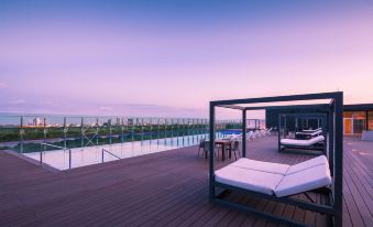 a rooftop lounge area with a canopy bed and a view of the ocean at sunset at Radisson Hotel Santa Cruz