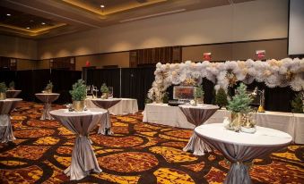 a large room with tables set up for an event , decorated with flowers and chandeliers at Osage Casino Hotel
