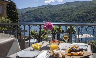 a dining table with a plate of food , a glass of wine , and a cup on it at Hotel Orso Bruno