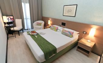 a large bed with a white and green blanket is in a room with wooden floors at Hotel Forum