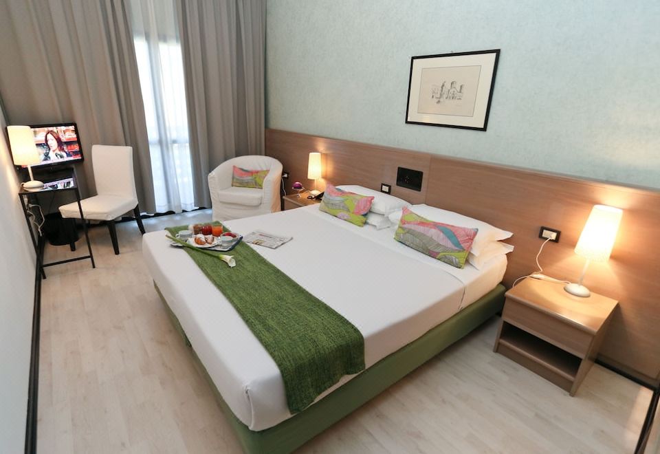 a large bed with a white and green blanket is in a room with wooden floors at Hotel Forum