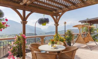 a wooden pergola with a table and chairs under it , overlooking a mountainous landscape under a blue sky at Miravalle