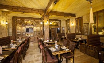 a restaurant with wooden tables and chairs , a marble floor , and a large open kitchen area at Kayakapi Premium Caves Cappadocia