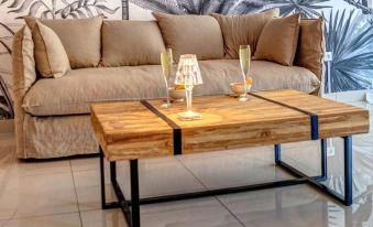 a wooden coffee table with two glasses of champagne and a knife on it , placed in front of a couch with a tropical wall mural at Hotel Pelican