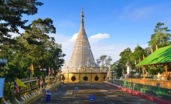 a tall , golden pagoda surrounded by trees and other buildings , with a blue sky in the background at Asian Hotel