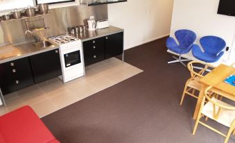 a modern kitchen with black cabinets , stainless steel appliances , and blue chairs near a red couch at Craggy Peaks