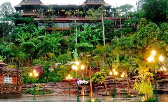 a large building surrounded by lush greenery , with a swimming pool in the foreground and trees surrounding it at Phu Pha Nam Resort