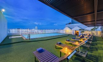 There is a patio with tables and chairs located next to the swimming pool at an apartment complex at Graph Hotels