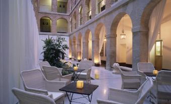 a courtyard with several white wicker chairs and tables arranged for outdoor dining or relaxation at Parador de La Granja