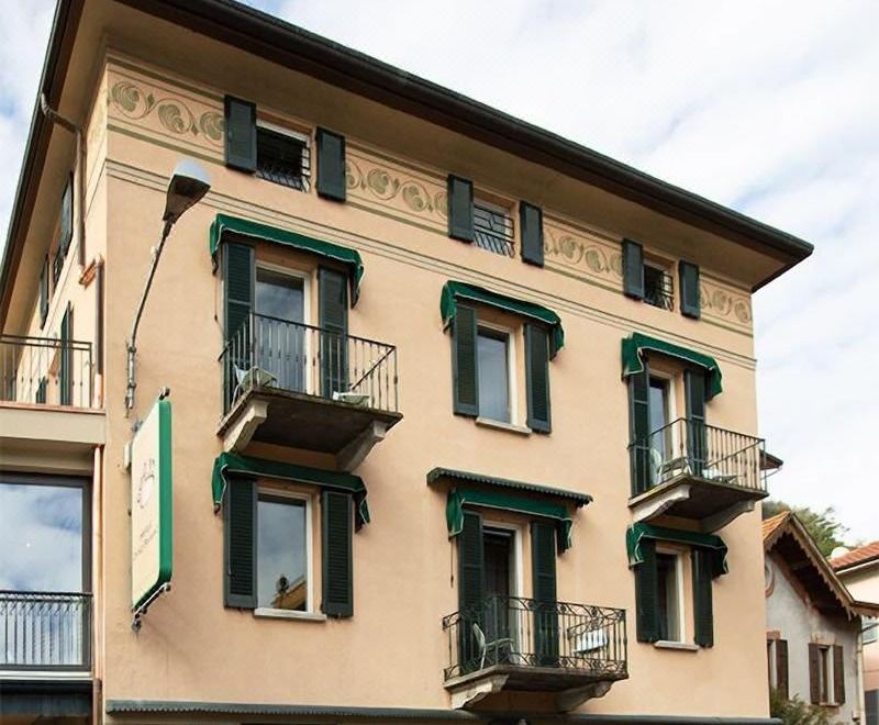 a three - story building with green shutters on its windows and balconies , located in a residential area at Hotel Orso Bruno