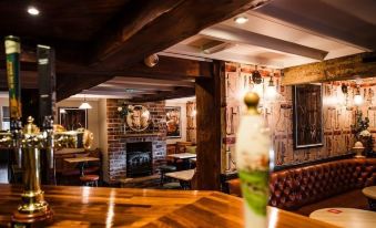 a cozy wooden bar with a fireplace , surrounded by people sitting and enjoying the ambiance at The Black Horse Inn