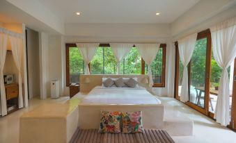 a large , white bed with multiple pillows is situated in a room with two windows at Proud Phu Fah Maerim Resort