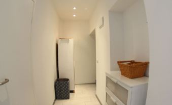 a hallway with white walls and a tiled floor , featuring a shoe rack and a suitcase at Downtown Apartments