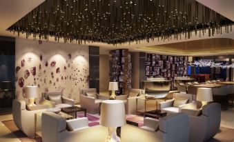 a modern lounge area with a large couch , lamps , and a chandelier hanging from the ceiling at Park Hyatt Doha