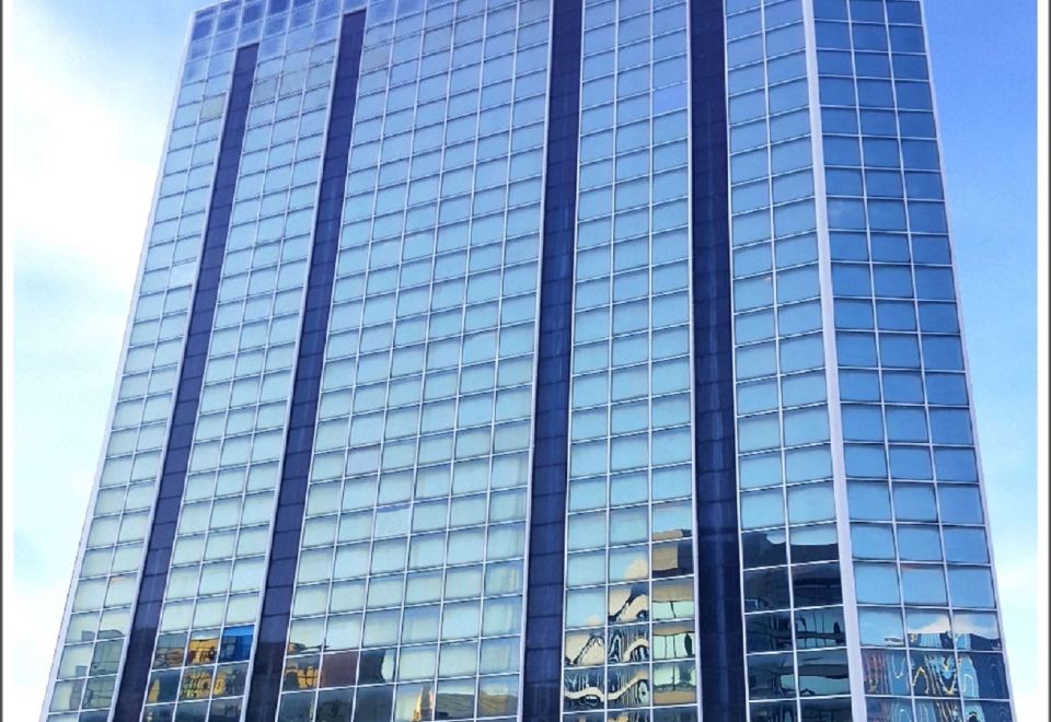 In front of an office tower, there is a tall building with many windows on its side at Best Western Plus Hotel Kowloon